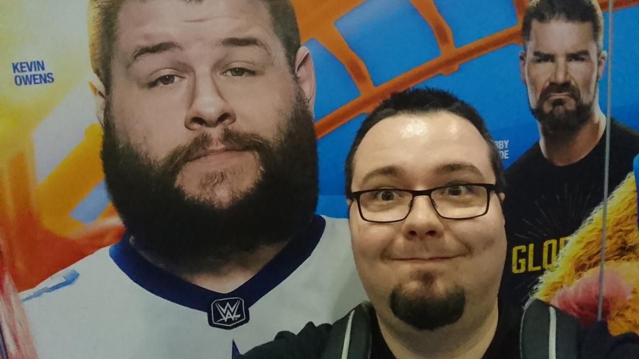 [02/04/2017] Die Schlange für ein Treffen mit Kevin Owens bei Axxess war so lang, dass sich Chris für ein Selfie mit einer Posterwand entscheidet. So ist wenigsten noch Bobby Roode mit drauf.