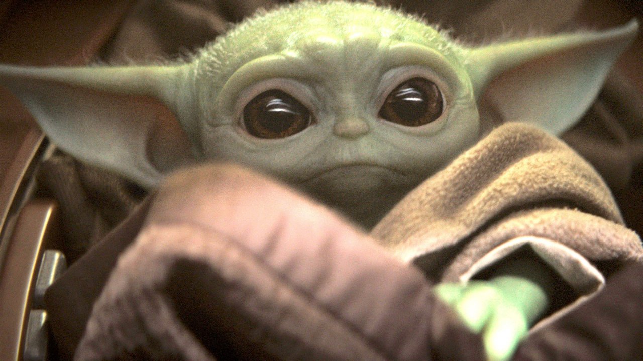 Baby Yoda blickt mit Welpen-Blick in die Kamera.