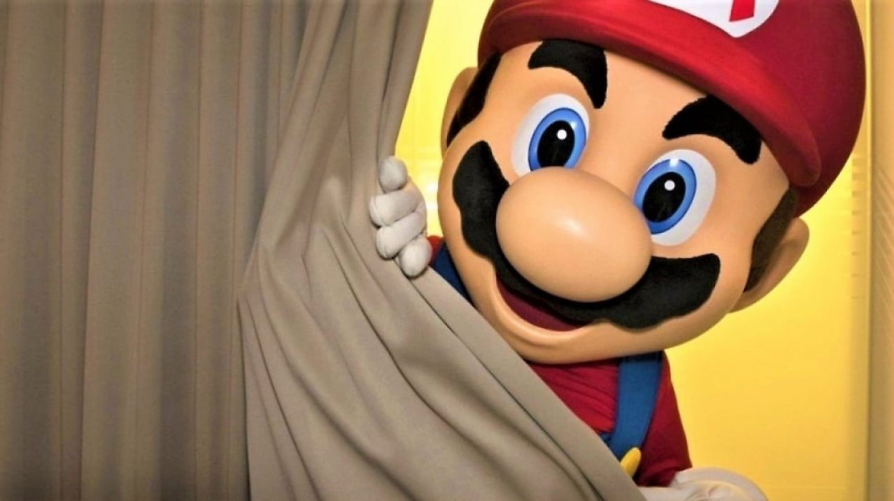 Das Nintendo-Maskottchen Super Mario spitzt hinter einem Vorhang hervor