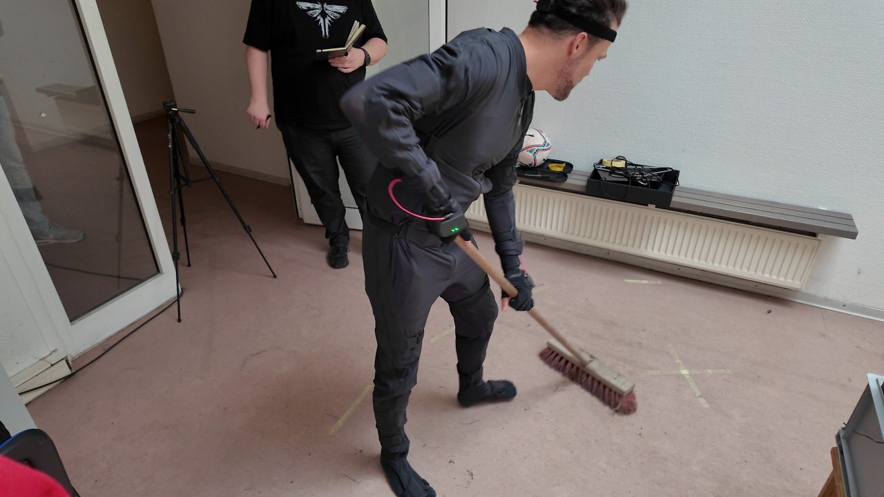 [22/01/2026] Animationschef Guido Neumann führt uns den Motion-Capture-Anzug vor und demonstriert, wie die Bewegung eines fegenden Menschen aufgezeichnet wird.