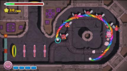 Wir steuern Kirby indirekt auf regenbogenfarbenen Schienen.