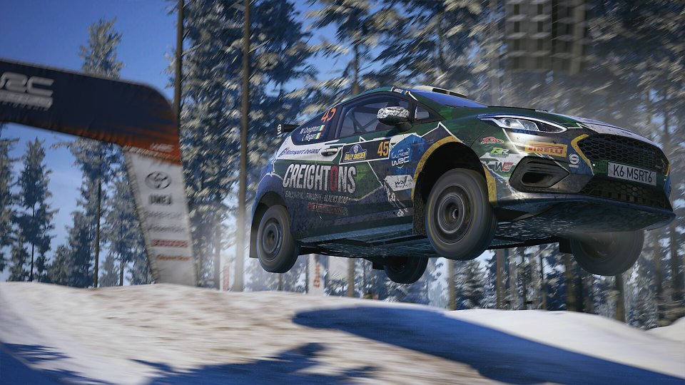 Ein Rennauto springt über eine verschneite Kuppe.